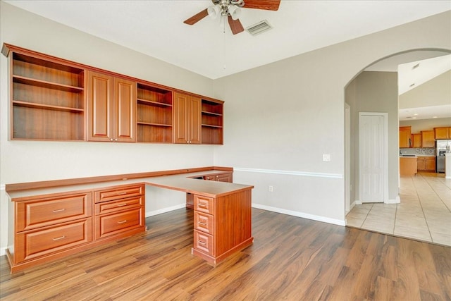 office featuring lofted ceiling, ceiling fan, light wood-type flooring, and built in desk