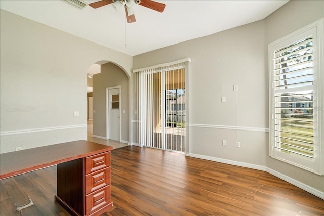 unfurnished office with ceiling fan and dark wood-type flooring