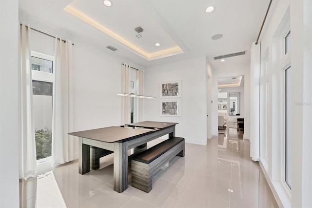 dining room featuring a tray ceiling and light tile patterned floors