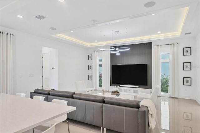 tiled living room with a raised ceiling and a notable chandelier