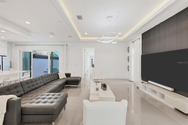 living room with an inviting chandelier, light tile patterned floors, and a tray ceiling