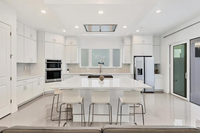 kitchen with white cabinets, a center island, stainless steel appliances, and a breakfast bar area