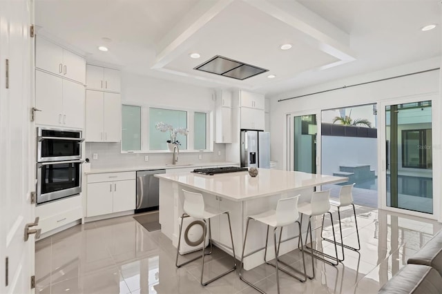 kitchen featuring backsplash, white cabinets, a kitchen island, and stainless steel appliances