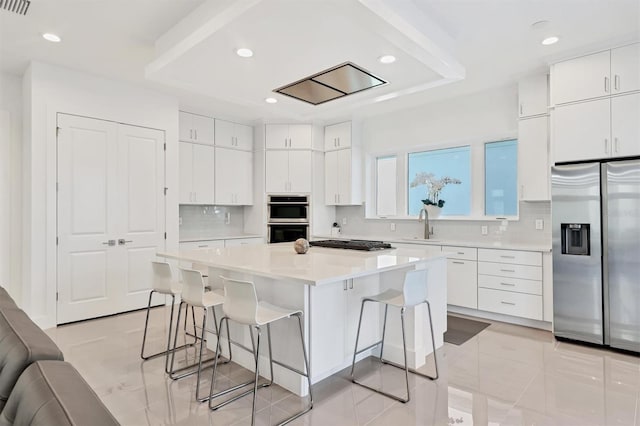 kitchen featuring white cabinets, a breakfast bar area, decorative backsplash, a kitchen island, and stainless steel appliances