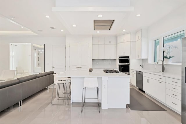 kitchen with stainless steel appliances, a kitchen island, white cabinetry, and sink