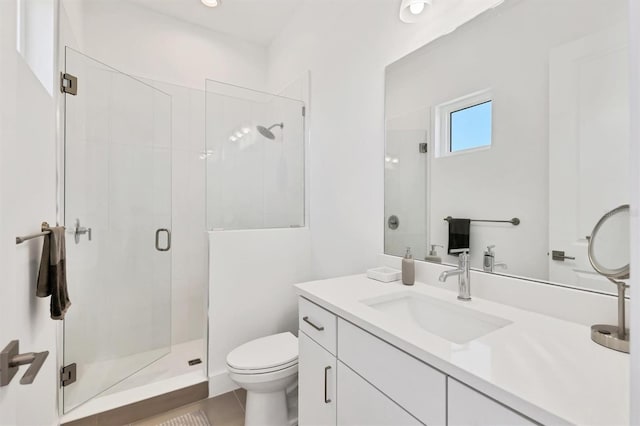 bathroom featuring tile patterned flooring, vanity, a shower with shower door, and toilet