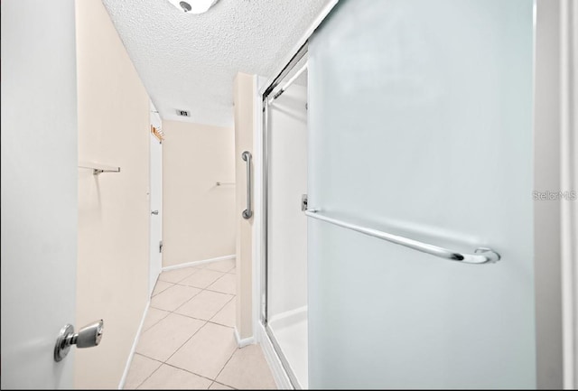 bathroom featuring tile patterned flooring, a shower with shower door, and a textured ceiling