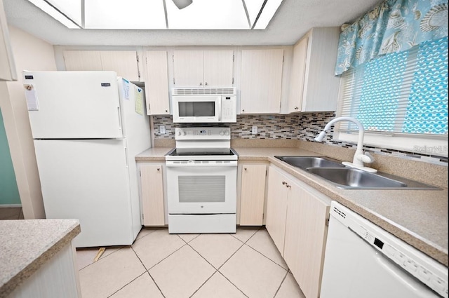 kitchen featuring a skylight, sink, white appliances, decorative backsplash, and light tile patterned floors