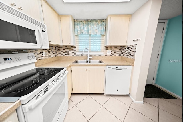 kitchen featuring tasteful backsplash, white appliances, sink, light tile patterned floors, and cream cabinets