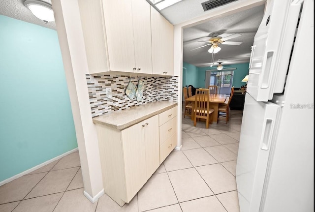 kitchen featuring backsplash, white refrigerator, ceiling fan, light tile patterned floors, and a textured ceiling