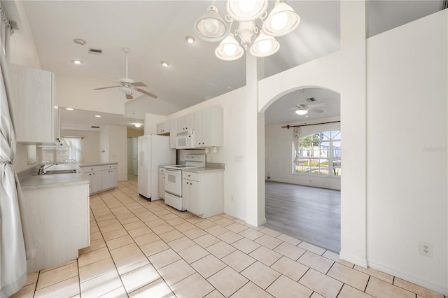 kitchen featuring sink, white cabinetry, vaulted ceiling, light tile patterned floors, and white appliances