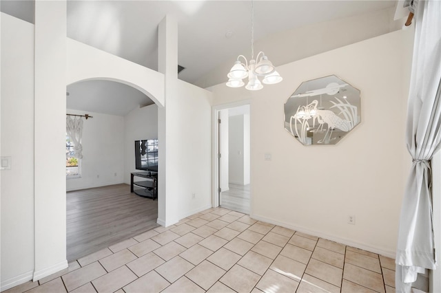 unfurnished dining area featuring light tile patterned floors, vaulted ceiling, and a chandelier