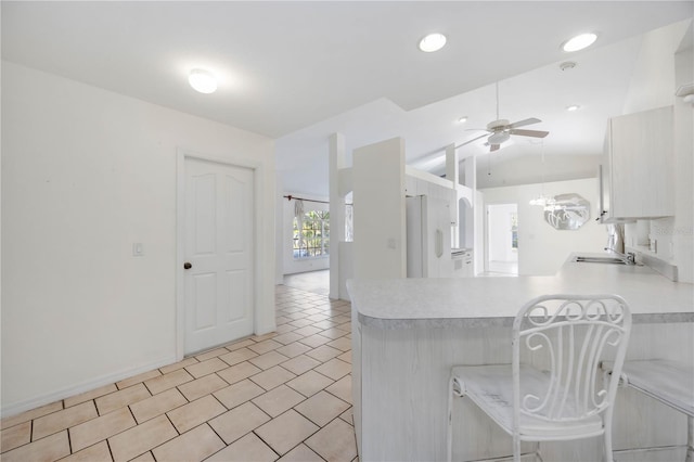 kitchen with sink, vaulted ceiling, white refrigerator, kitchen peninsula, and ceiling fan