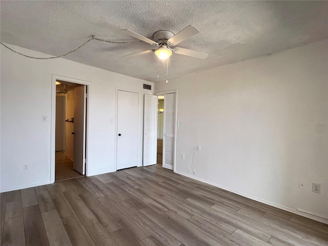 unfurnished bedroom with ceiling fan, wood-type flooring, and a textured ceiling