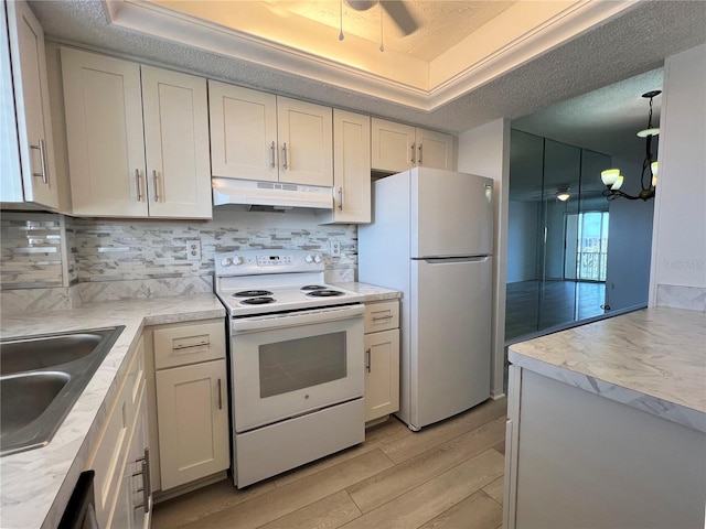 kitchen with light wood-type flooring, a textured ceiling, white appliances, and backsplash