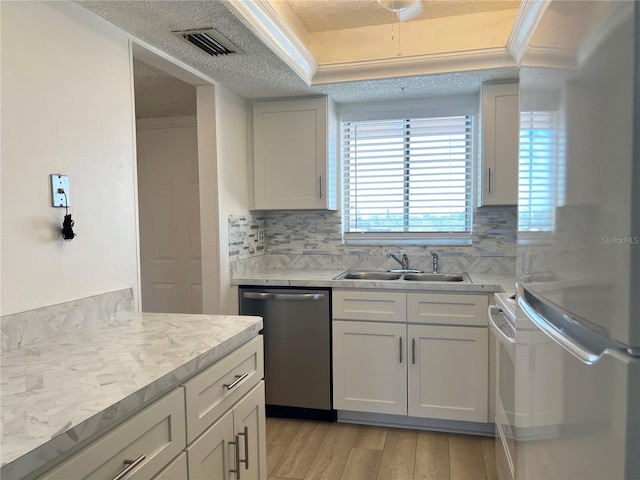 kitchen featuring sink, light wood-type flooring, a textured ceiling, tasteful backsplash, and stainless steel appliances