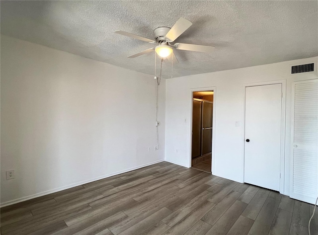 unfurnished bedroom with a textured ceiling, ceiling fan, dark wood-type flooring, and a closet