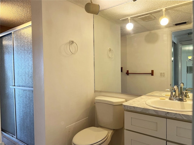 bathroom featuring vanity, a textured ceiling, toilet, and a shower with shower door