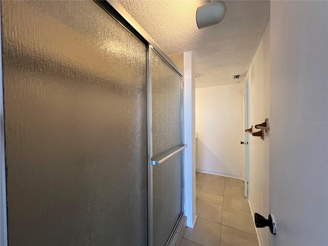 bathroom featuring a textured ceiling, tile patterned floors, and a shower with shower door