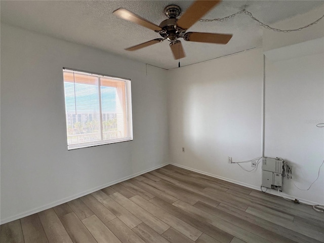 empty room with ceiling fan, wood-type flooring, and a textured ceiling