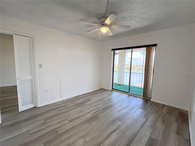 empty room with ceiling fan, light hardwood / wood-style floors, and a textured ceiling