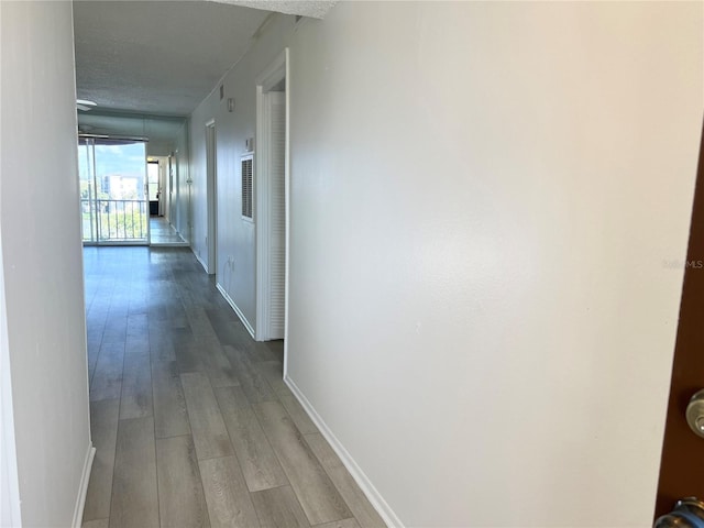 corridor with wood-type flooring and a textured ceiling