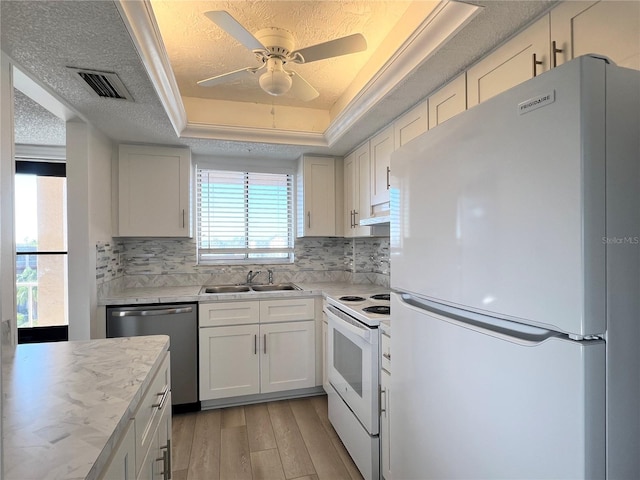 kitchen with sink, white cabinetry, a raised ceiling, white appliances, and decorative backsplash