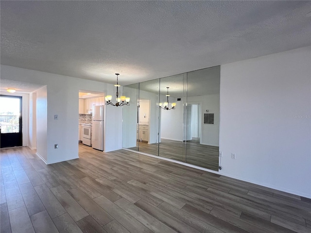 interior space featuring an inviting chandelier, wood-type flooring, and a textured ceiling