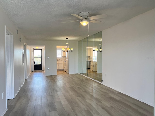 spare room with hardwood / wood-style floors, ceiling fan with notable chandelier, and a textured ceiling