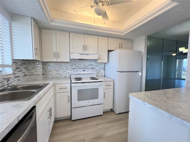 kitchen with sink, white appliances, white cabinetry, tasteful backsplash, and a raised ceiling