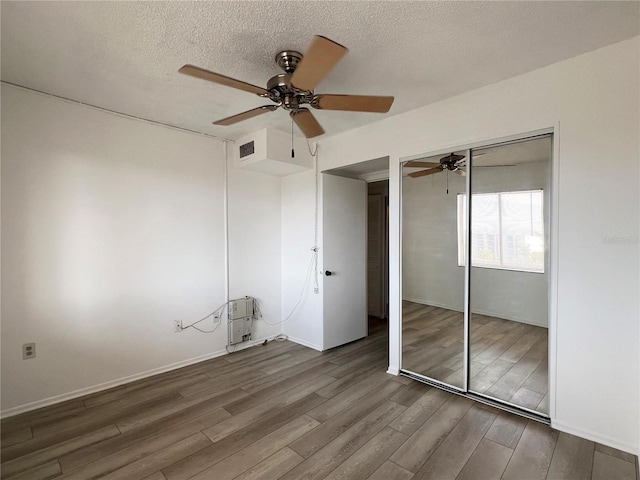 unfurnished bedroom featuring ceiling fan, hardwood / wood-style flooring, a closet, and a textured ceiling