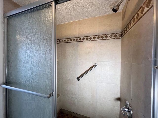 bathroom with a shower with shower door and a textured ceiling