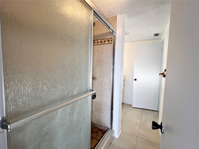 bathroom with tile patterned flooring, a textured ceiling, and a shower with shower door