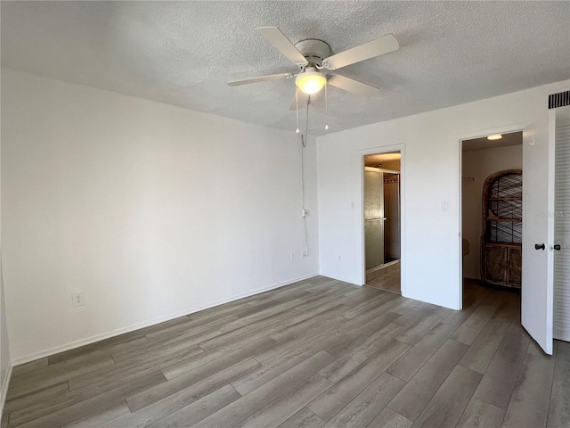 unfurnished bedroom featuring a walk in closet, hardwood / wood-style floors, a closet, and a textured ceiling