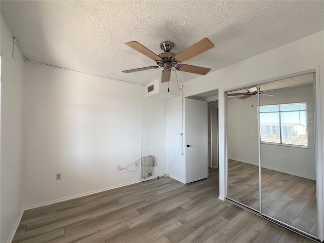 unfurnished bedroom with hardwood / wood-style flooring, a textured ceiling, a closet, and ceiling fan