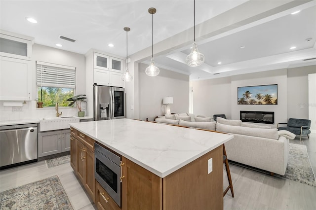 kitchen featuring pendant lighting, a center island, sink, white cabinetry, and stainless steel appliances