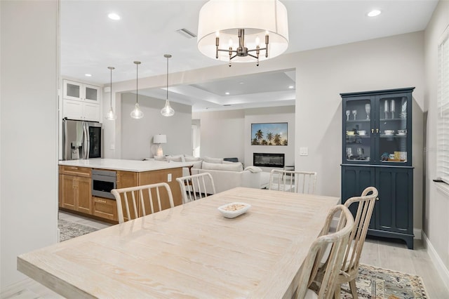 dining room with a tray ceiling, light hardwood / wood-style floors, and a notable chandelier