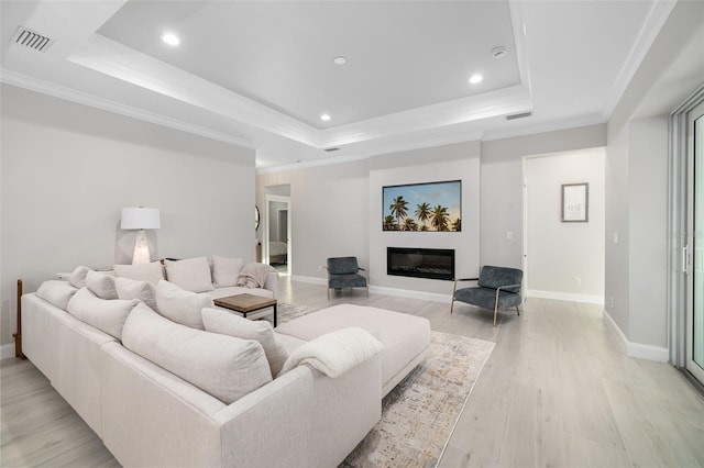 living room with crown molding, light hardwood / wood-style flooring, and a tray ceiling