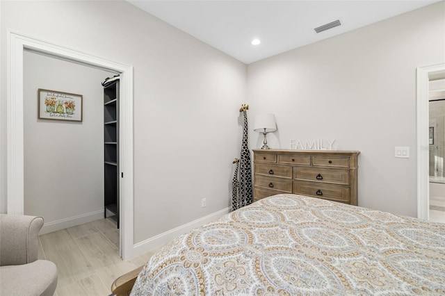 bedroom with a walk in closet and light hardwood / wood-style floors