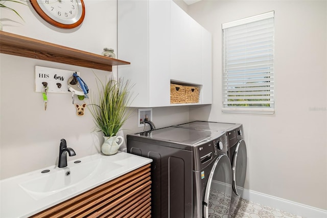 clothes washing area with washer and clothes dryer, cabinets, and sink