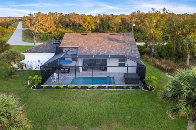 back of property featuring a lawn, glass enclosure, and a patio area