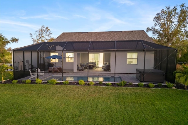 rear view of property featuring a lanai, a patio area, a yard, and a hot tub