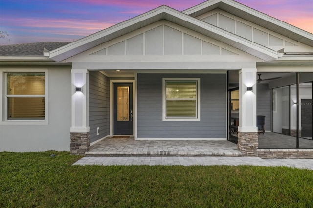 exterior entry at dusk featuring covered porch and a yard