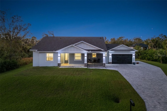 view of front of house with covered porch, a garage, and a front lawn