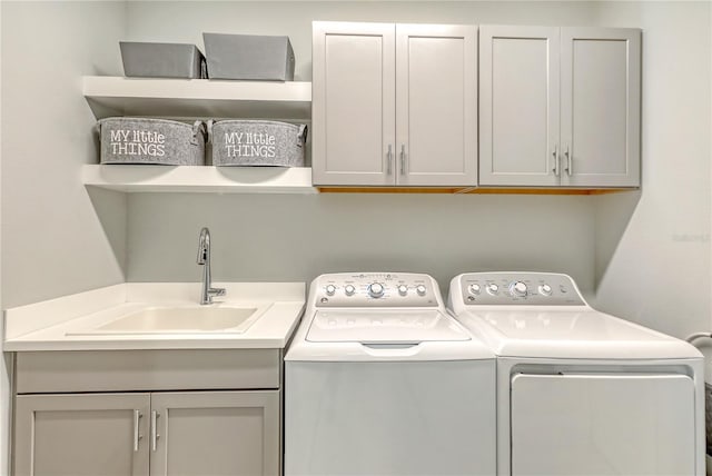 clothes washing area featuring cabinets, washing machine and dryer, and sink