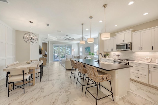 kitchen featuring stainless steel appliances, white cabinetry, and hanging light fixtures