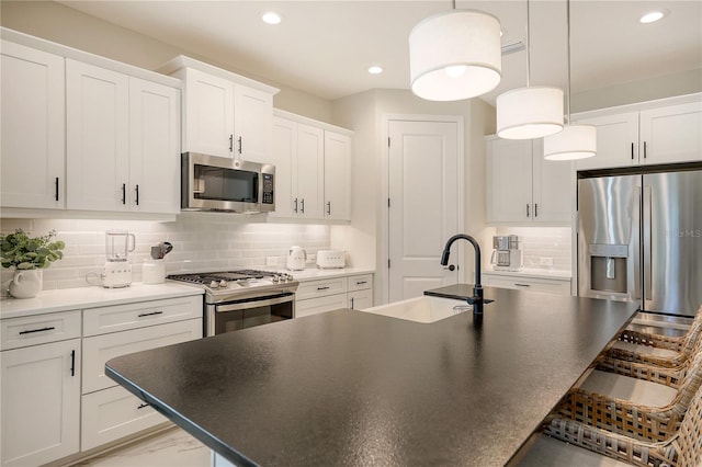 kitchen with decorative backsplash, stainless steel appliances, sink, pendant lighting, and white cabinets