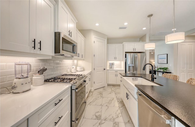 kitchen with pendant lighting, stainless steel appliances, and white cabinetry