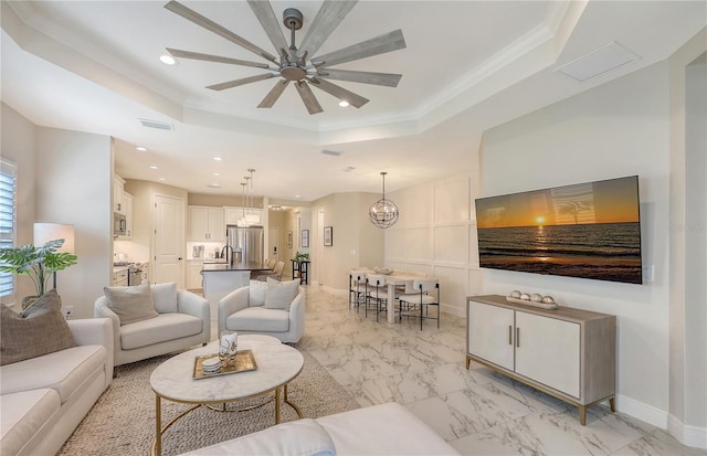 living room with ceiling fan with notable chandelier, a raised ceiling, and ornamental molding