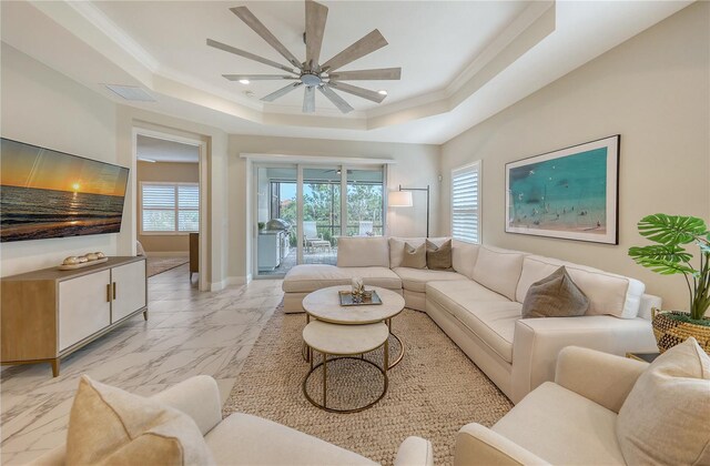 living room featuring a tray ceiling, ceiling fan, and ornamental molding